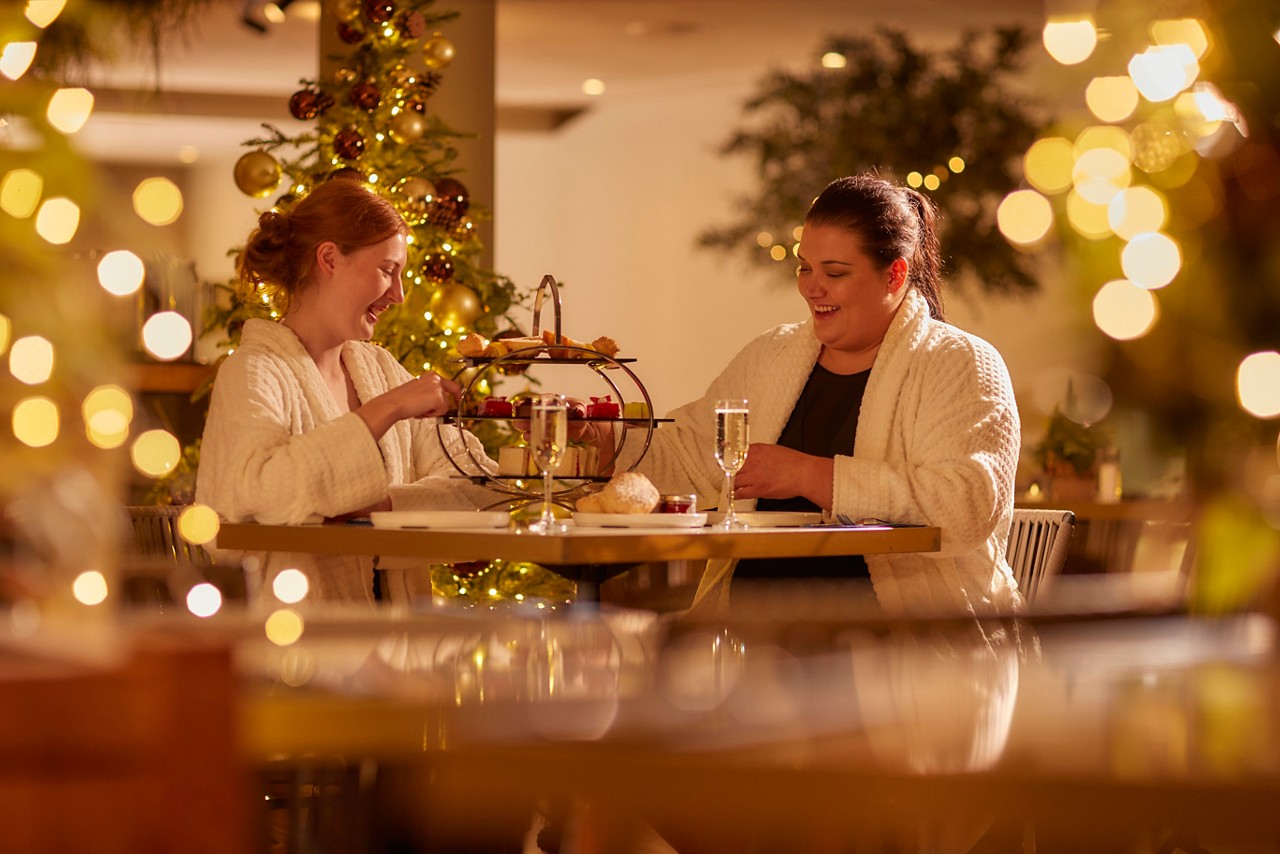 Two women eating a Festive Afternnon Tea in the Vitalé Café Bar.